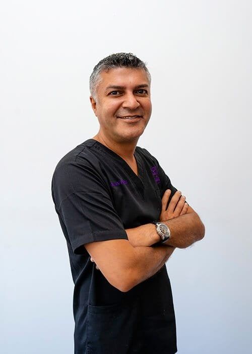 Smiling professional in medical scrubs with arms crossed.