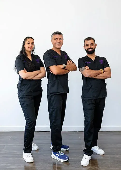 Three medical professionals in scrubs, smiling.