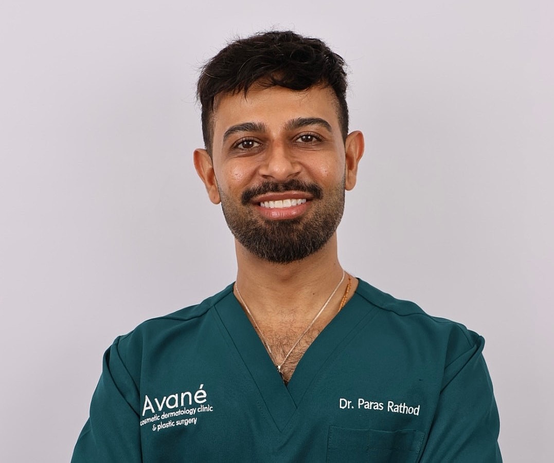 Smiling professional in medical scrubs with crossed arms.