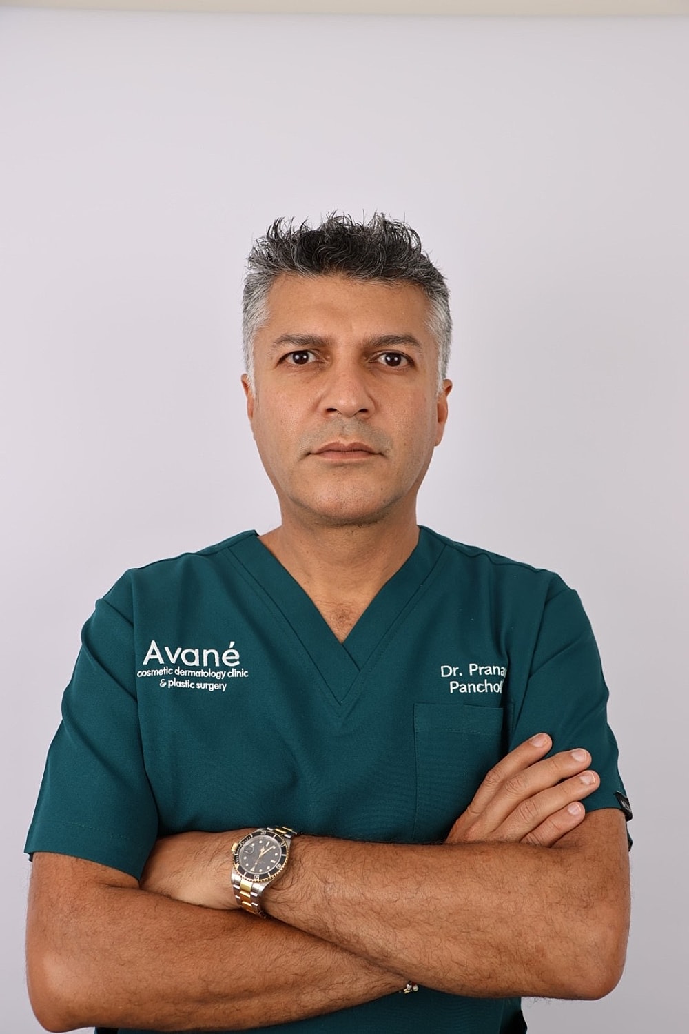 Smiling professional in medical scrubs with crossed arms.