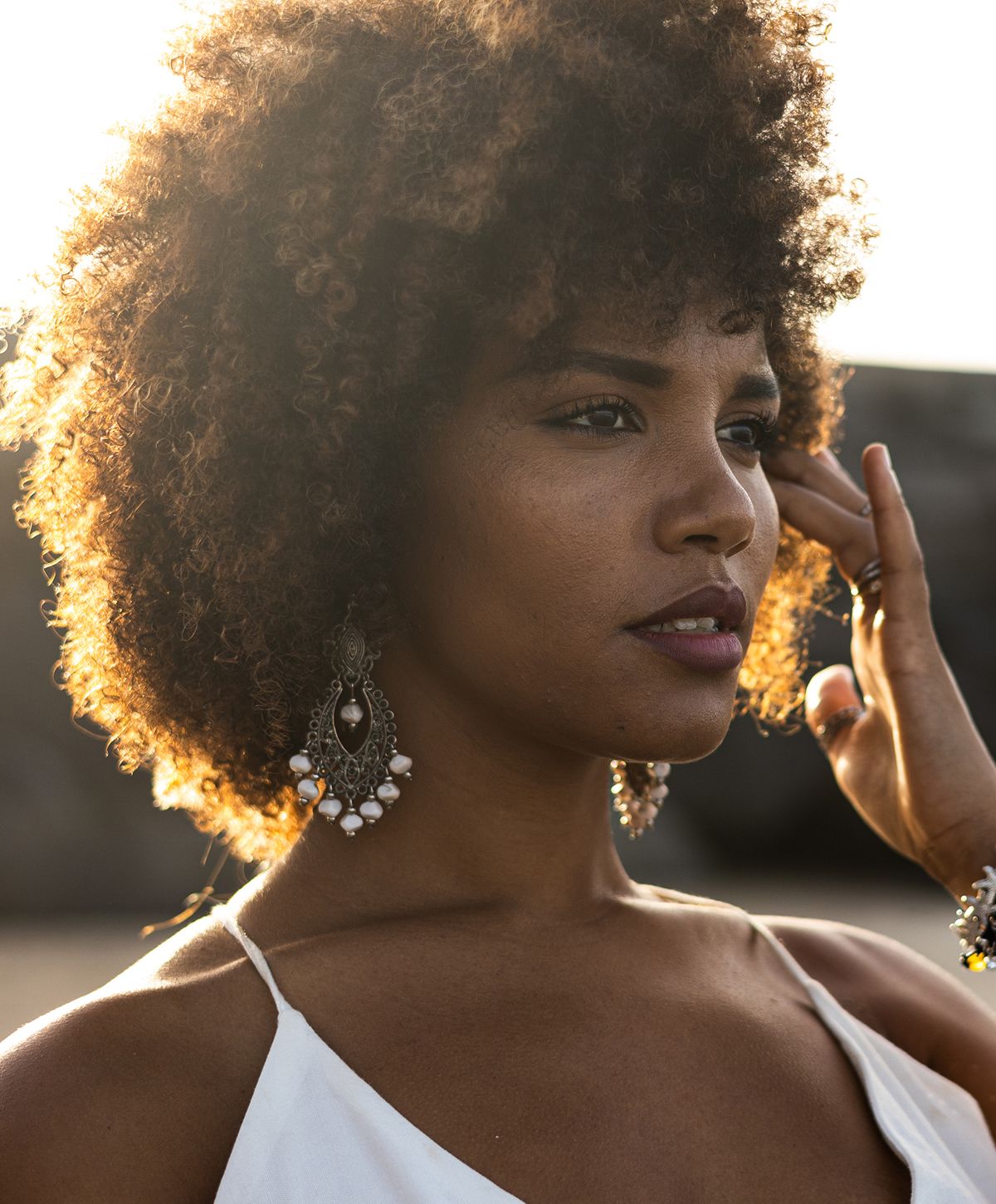 Smiling woman with curly hair against gray background.