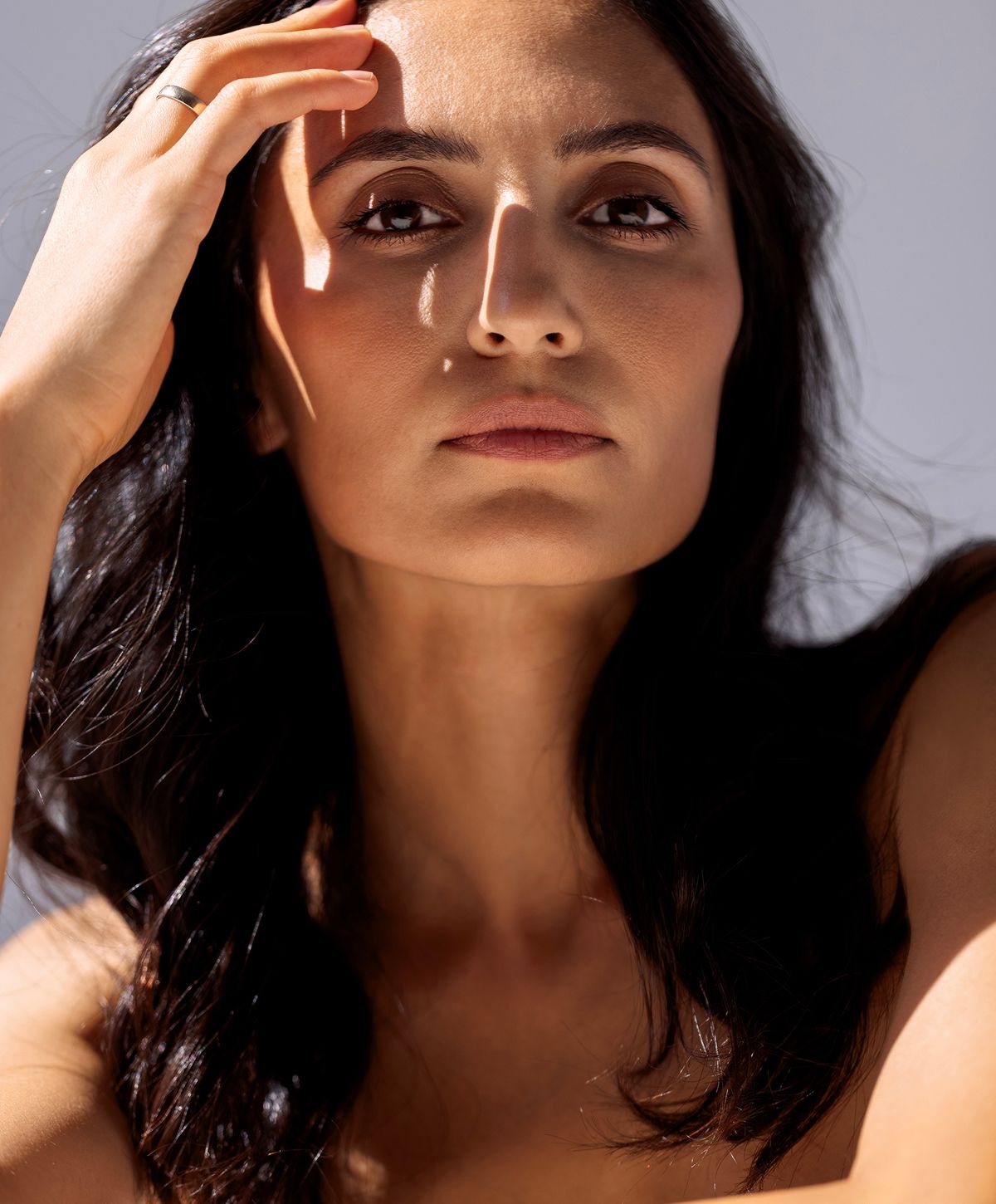 Woman with braided hair displaying gold jewelry.