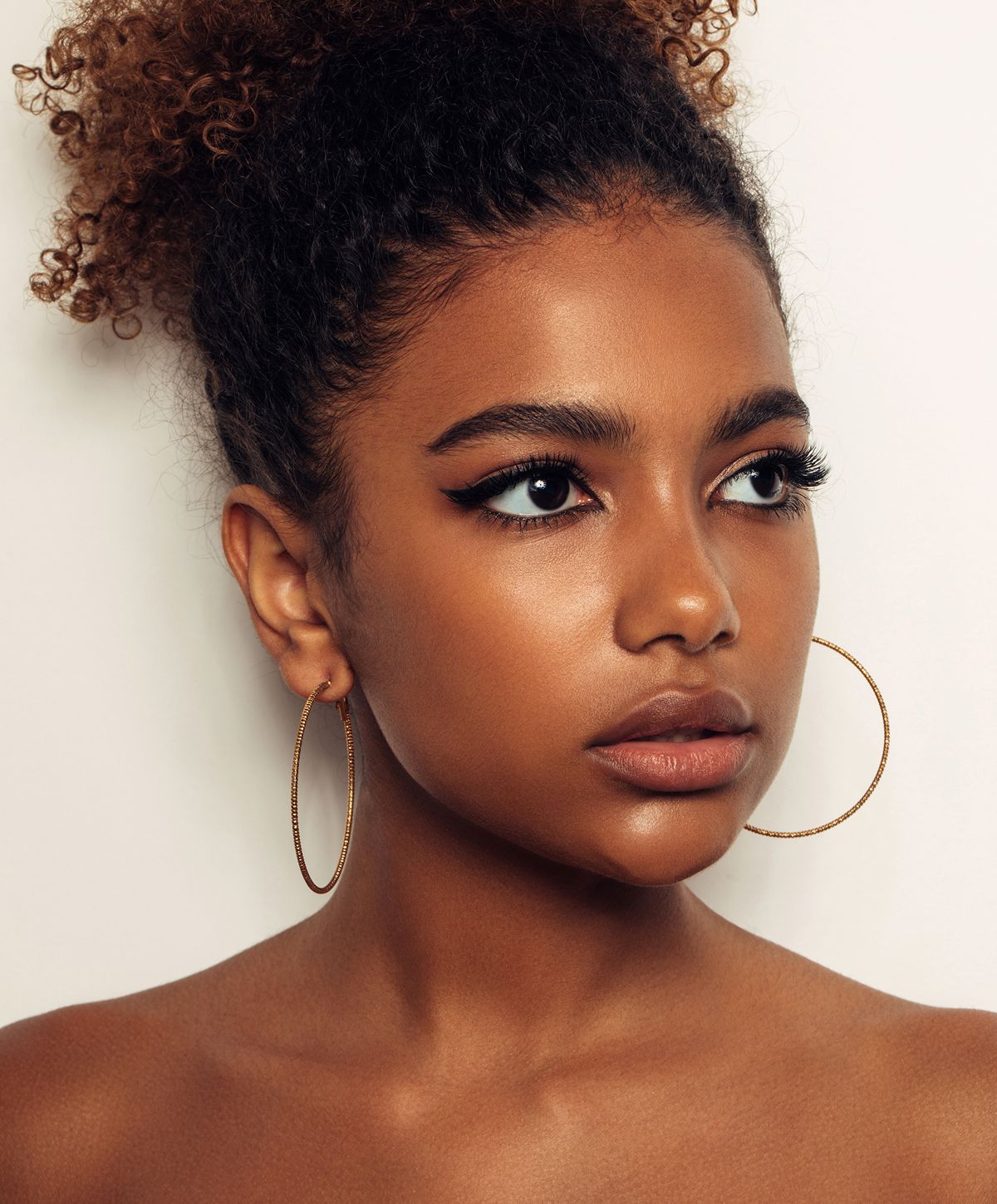 Smiling woman touching her face in soft lighting.