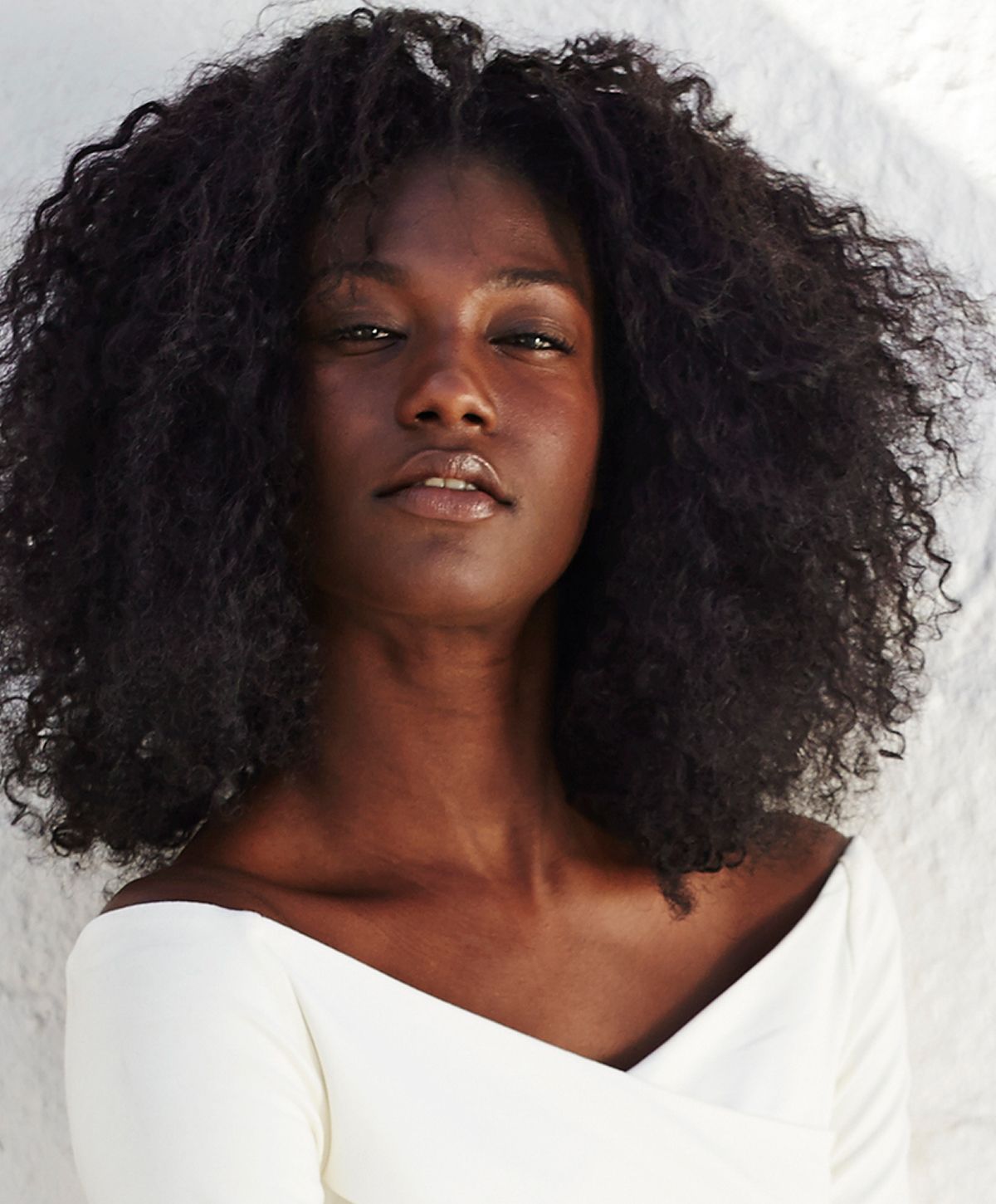 Woman with braided hair displaying gold jewelry.