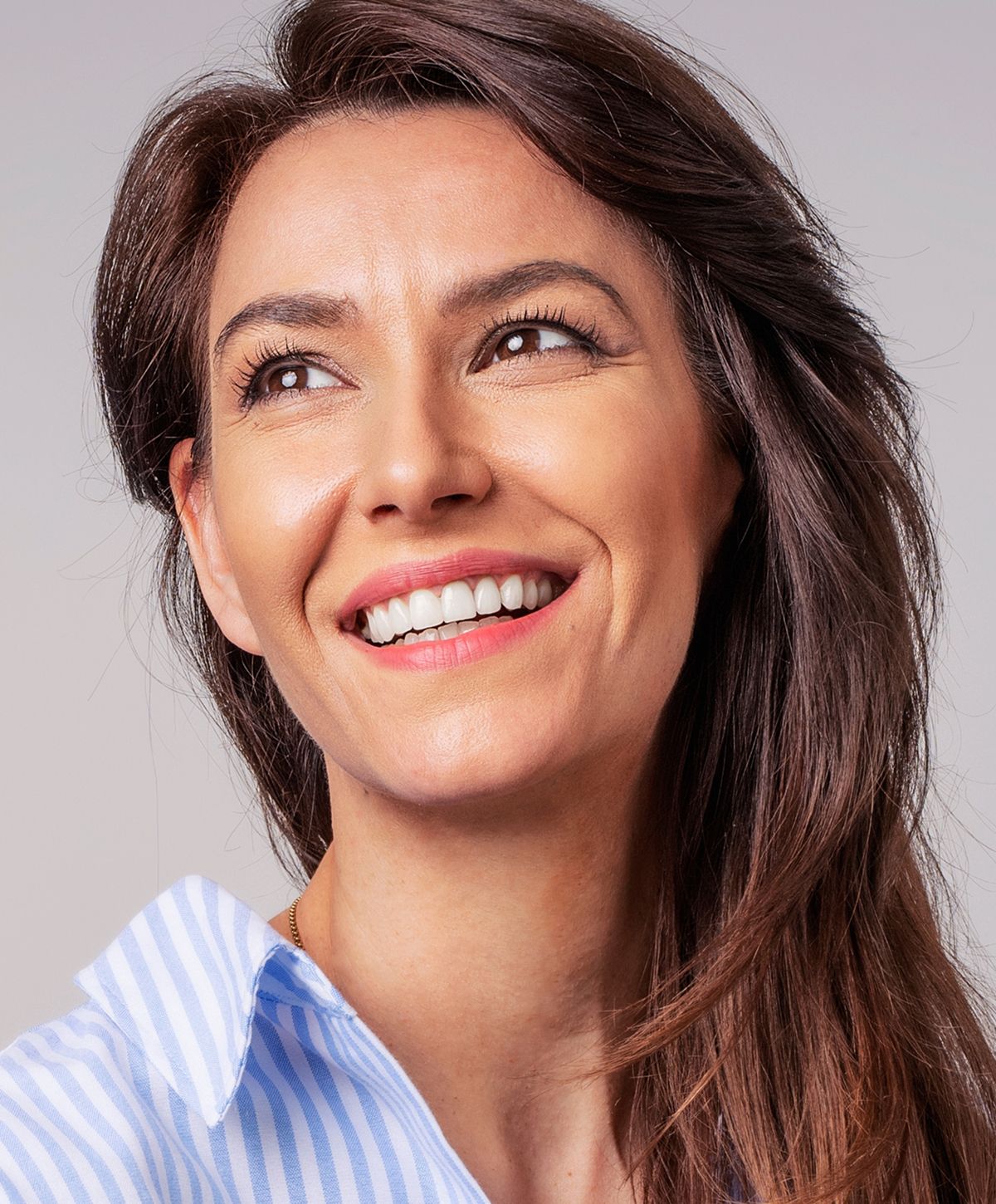 Woman with braided hair displaying gold jewelry.