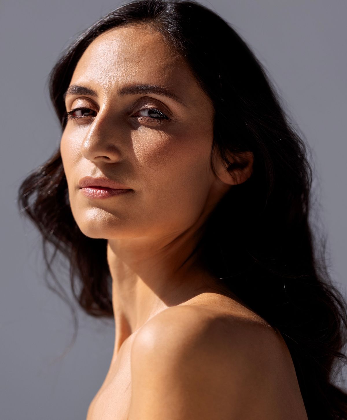 Woman with braided hair displaying gold jewelry.