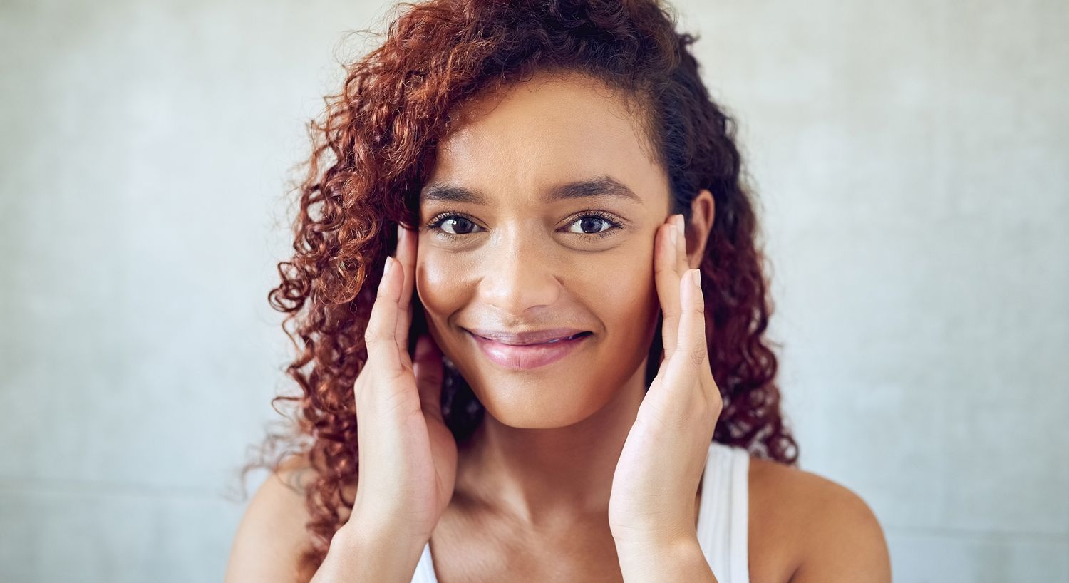 Smiling woman touching her face, relaxed expression.