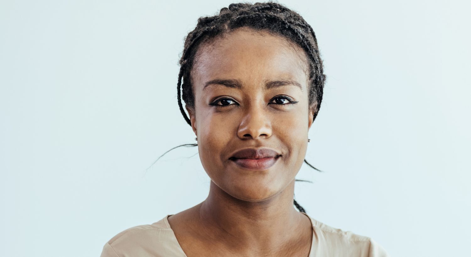 Woman applying skincare, smiling at camera.