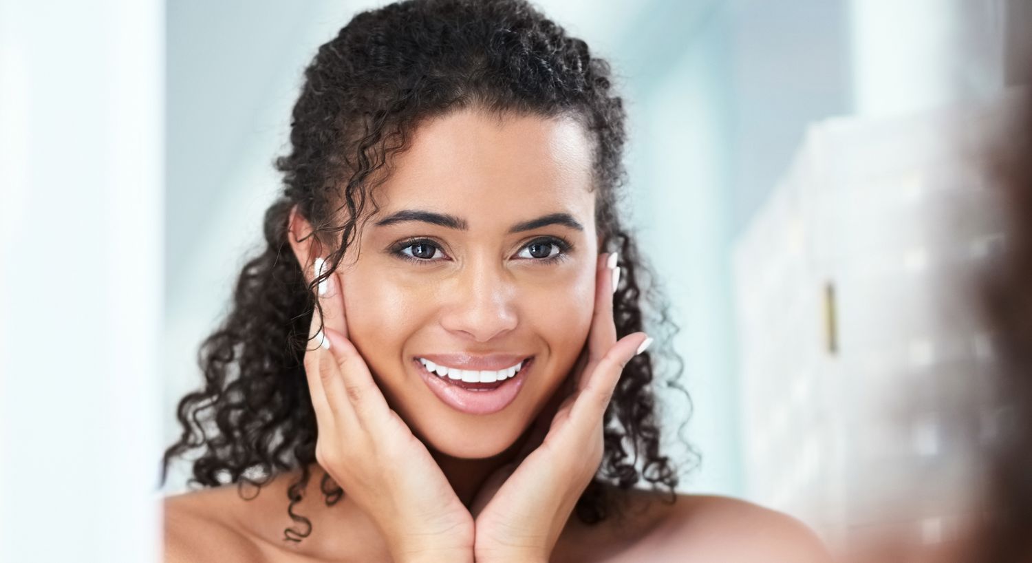 Smiling woman admiring her reflection in mirror.